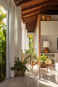 A modern living room with wood and brick elements, featuring a wooden floor, white walls, and large windows with greenery out