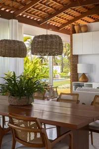 Modern dining room featuring bamboo furniture and large windows overlooking a pool and tropical garden.