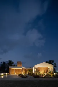 A modern entryway illuminated at night with wooden accents, cement flooring, and strategic lighting.