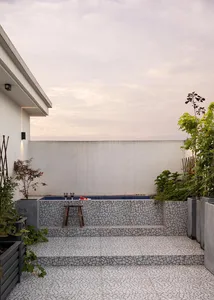 Modern outdoor living area with concrete deck, plants, and a small pool.