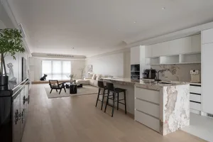 A minimalist residential kitchen featuring marble finishes and white accents.