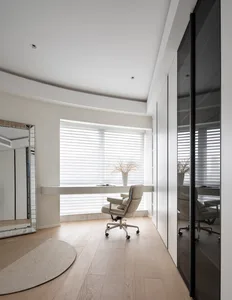 A modern minimalist home office featuring a white marble desk and chair, with sleek white furniture and natural light streami