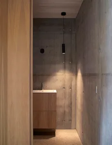 A minimalist bathroom with concrete walls and wooden vanity.