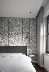 Modern, minimalist bedroom with a grey fabric headboard, white bedding, and geometric wallpaper.