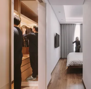 A modern bedroom with wood flooring, fabric curtains, and metallic furniture.