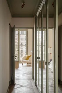 Modern minimalist apartment interior with wooden flooring, featuring a cozy lounge area with a yellow cushion and a spacious