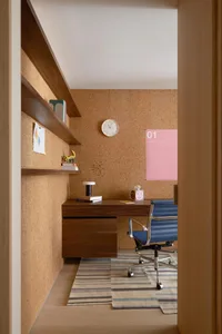 A modern minimalist home office with a wooden desk and chair, wooden walls, and a clock on the wall.