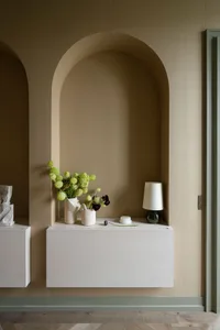 A modern residential entryway featuring a concrete floating shelf with a lamp and flowers.