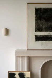 A minimalistic interior with a concrete mantel featuring abstract artwork on the wall.