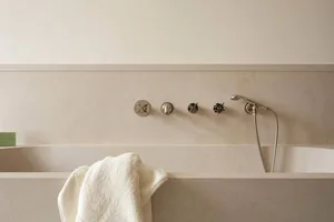 Modern bathroom with a minimalist design featuring a concrete bathtub and sleek, chrome fixtures.