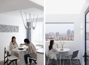 Two people sitting at a round dining table with white chairs and minimalist decor.
