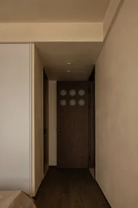 A minimalist bedroom doorway with wooden panels and circular cutouts.