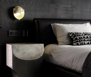 A modern bedroom featuring a concrete nightstand, a black leather bed, and a metal bedside lamp.