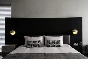 A modern bedroom featuring a black wooden headboard and a bed with white linens and patterned pillows.