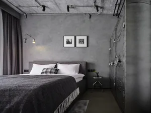 A bedroom with industrial design features, showcasing concrete walls and a large bed.