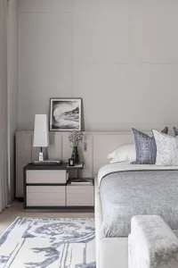 A modern minimalist bedroom featuring a bed with a fabric headboard and wooden nightstand.
