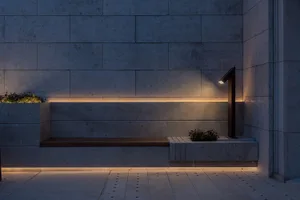 A modern concrete seating area with ambient lighting and plants.
