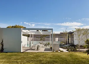 Modern house exterior with concrete walls and a glass pergola.