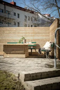 Modern outdoor wooden table and bench with a potted plant on top.