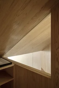 A window in a room with an angled ceiling and wooden paneling.