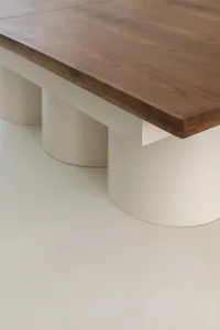 A minimalist table with a wooden top and white cylindrical bases.