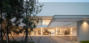 An illuminated showroom with glass walls and concrete elements, featuring luxury cars on display.