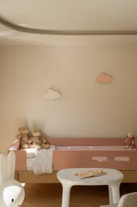 A minimalist child's bedroom featuring a wooden bunk bed with fabric bedding and stuffed animals.