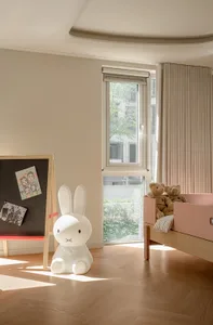 A minimalist children's room with wooden furniture and a white rabbit statue