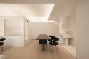 A minimalist office space with black furniture on light wood floors.