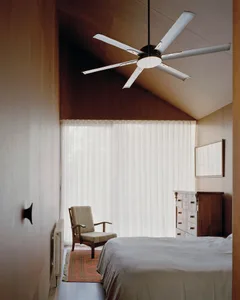 A minimalist bedroom with a white flat door, sheer white curtains, and a large window, featuring a bed with a white bedspread