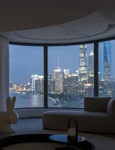 Modern living room with a glass wall overlooking a cityscape.