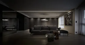 A modern living room with dark interior design, featuring dark wood flooring, dark sofas, and minimalist decor.