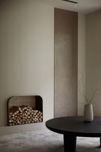 A minimalist living room featuring a round wooden table and a modern fireplace.