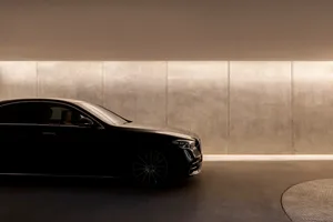 A sleek, black car interior with metallic elements set against a modern, illuminated wall.