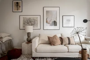 A minimalist living room with a white sofa, abstract art, and a concrete side table.