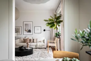 Modern minimalist living room with a white couch, plants, and art on the walls.