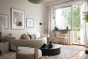 A minimalist living room with white fabric furniture and a black coffee table.