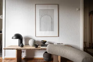 A minimalist living room with wooden furniture and a black table lamp on a wooden shelf.