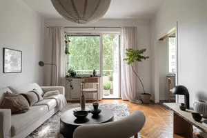 A minimalist living room with wooden flooring, a white sofa, and a circular coffee table in the center.