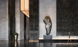 A modern lobby interior featuring a metallic sculpture of a horse's head mounted on the wall, set against a backdrop of polis