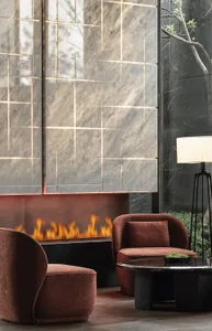 A modern living room with a marble fireplace and brown upholstered chairs.