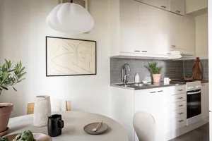 Modern minimal kitchen with white countertops, stainless steel appliances, and white porcelain tiles