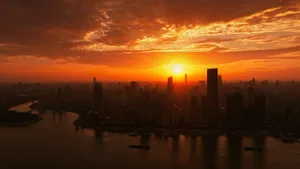 Aerial view of a city skyline at sunset with skyscrapers and a river.