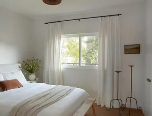 A minimalist bedroom with white curtains and a bed