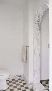 A minimalist bathroom featuring marble tile and checkered floor tiles.