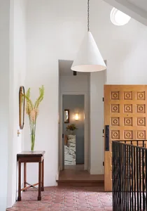 Modern entryway with floor of terrazzo and cement, featuring a wooden door with geometric design.