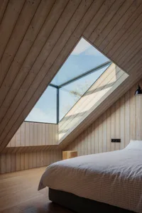 Modern bedroom with wood-paneled walls and a skylight.