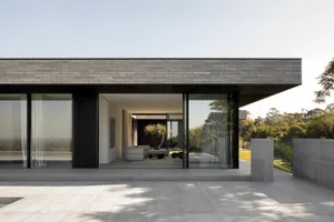 A modern concrete home featuring a minimalist design with large windows and a flat roof.