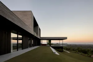 Modern residential building with large windows and a sloping roofline.