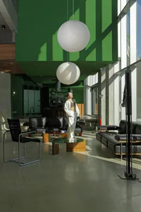 A modern minimalist living room with concrete walls, glass and metal furniture, and black leather sofas.